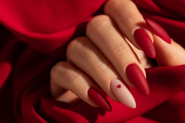 Matte red stiletto nails with heart nail art detail