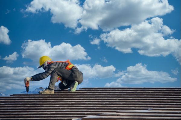 Worker performing roof inspection and maintenance under blue sky