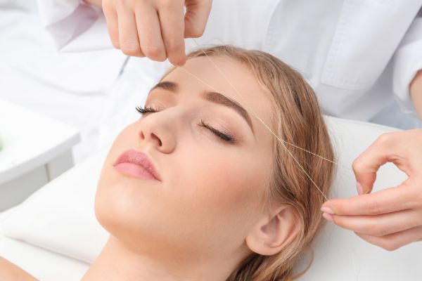 Woman getting eyebrow trimming service at beauty salon