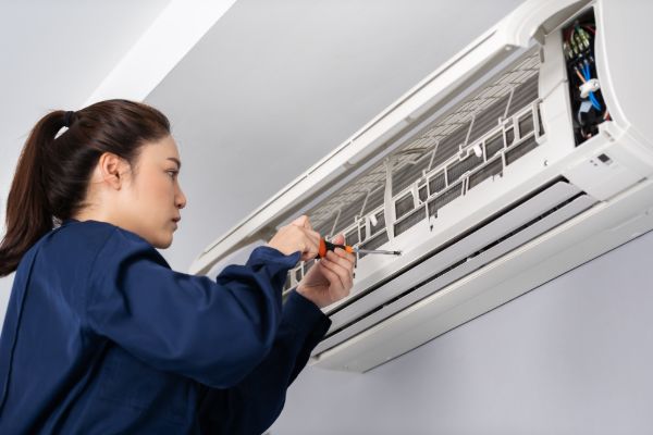 technician servicing air conditioner electrical unit