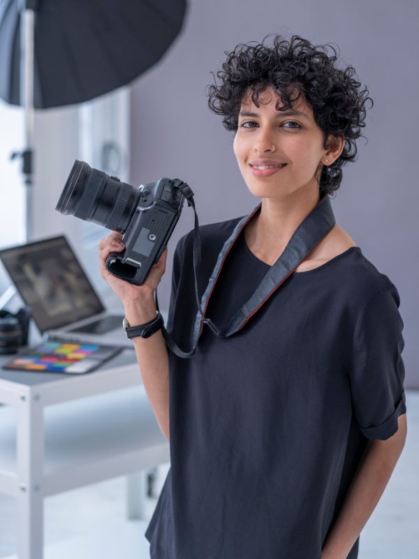 Female photographer holding camera in studio environment