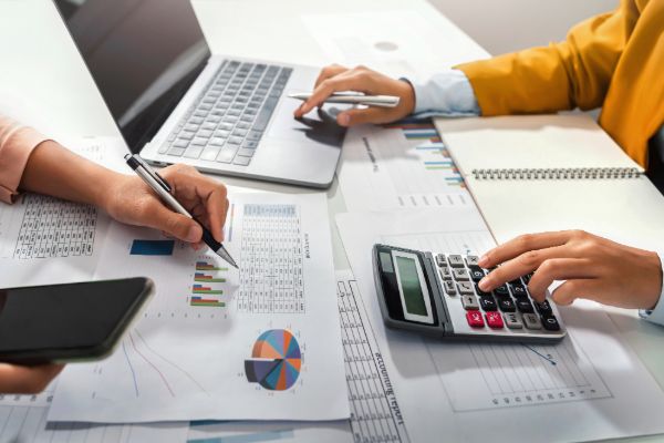 Hands using calculator and analyzing financial reports