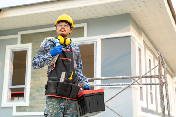 Home service contractor holding tools outside a house