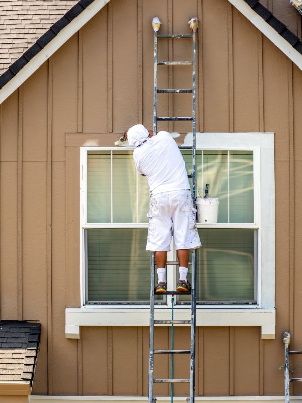 Professional painter working on exterior house painting using a ladder