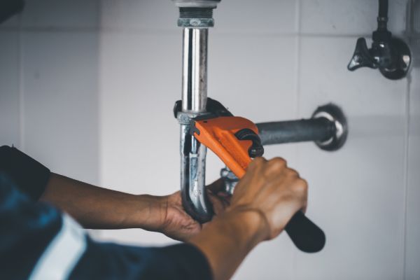 Plumber repairing bathroom pipe with wrench