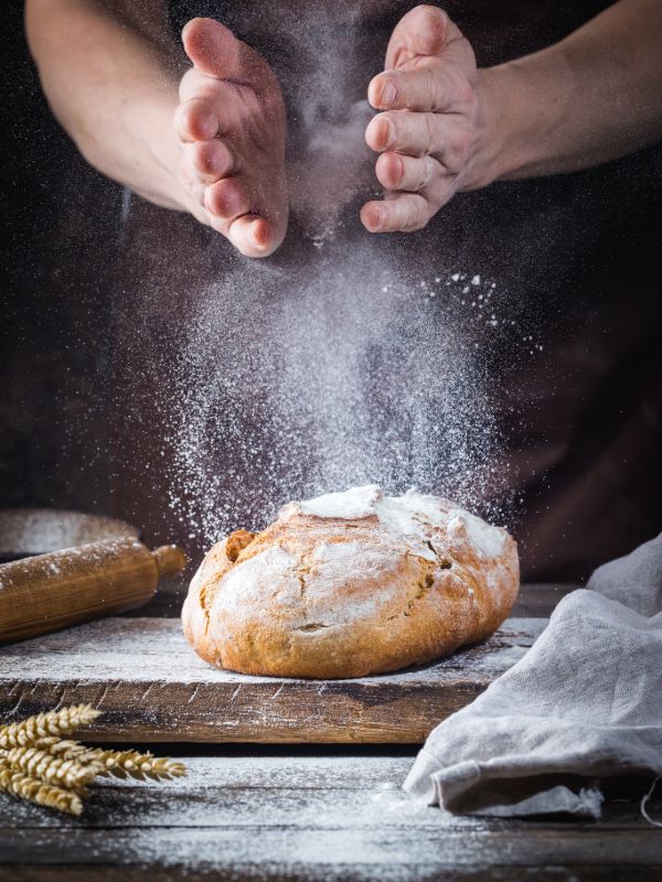 Baker preparing artisan bread with flour in a professional bakery kitchen