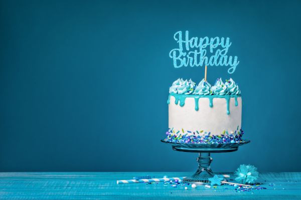 Birthday cake with candles and decorative frosting on a blue background