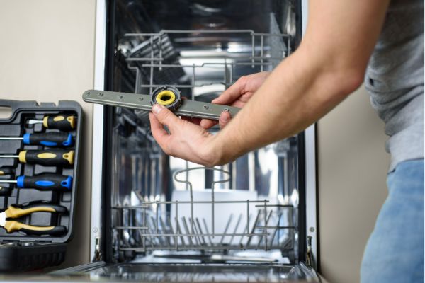 Repairing a dishwasher with tools in a kitchen
