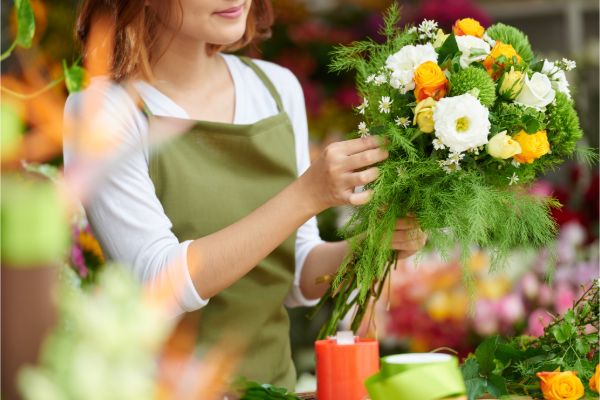 Florist holding a fresh bouquet arrangement in a flower shop