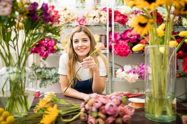 Florist standing inside a flower shop surrounded by fresh flowers and bouquets