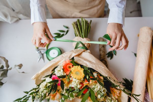Florist preparing and wrapping a colorful flower bouquet on a work table