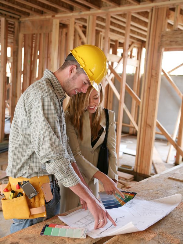 Home builder reviewing construction plans at building site