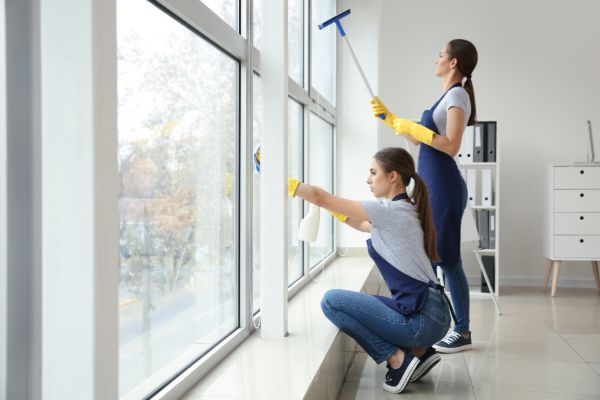 Professional cleaners washing large indoor residential windows