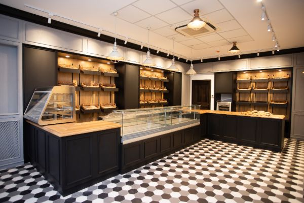 Modern bakery interior with bread shelves, display counters, and seating area
