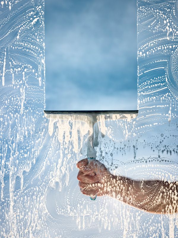 Professional window cleaner washing large glass windows with cleaning tools