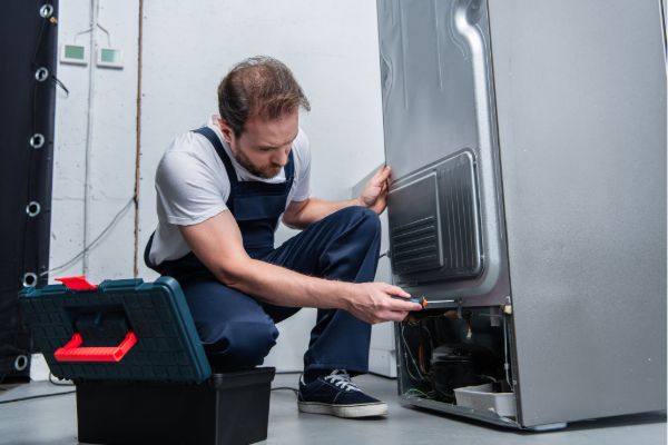 Technician fixing a refrigerator at home