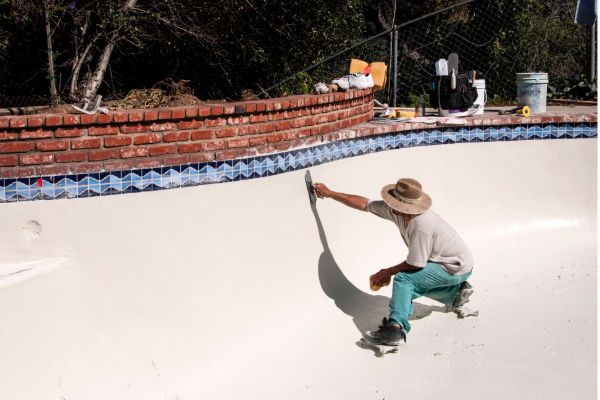 Pool contractor resurfacing and renovating an empty residential swimming pool