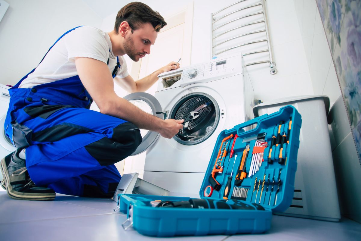 Technician repairing a washing machine with tools
