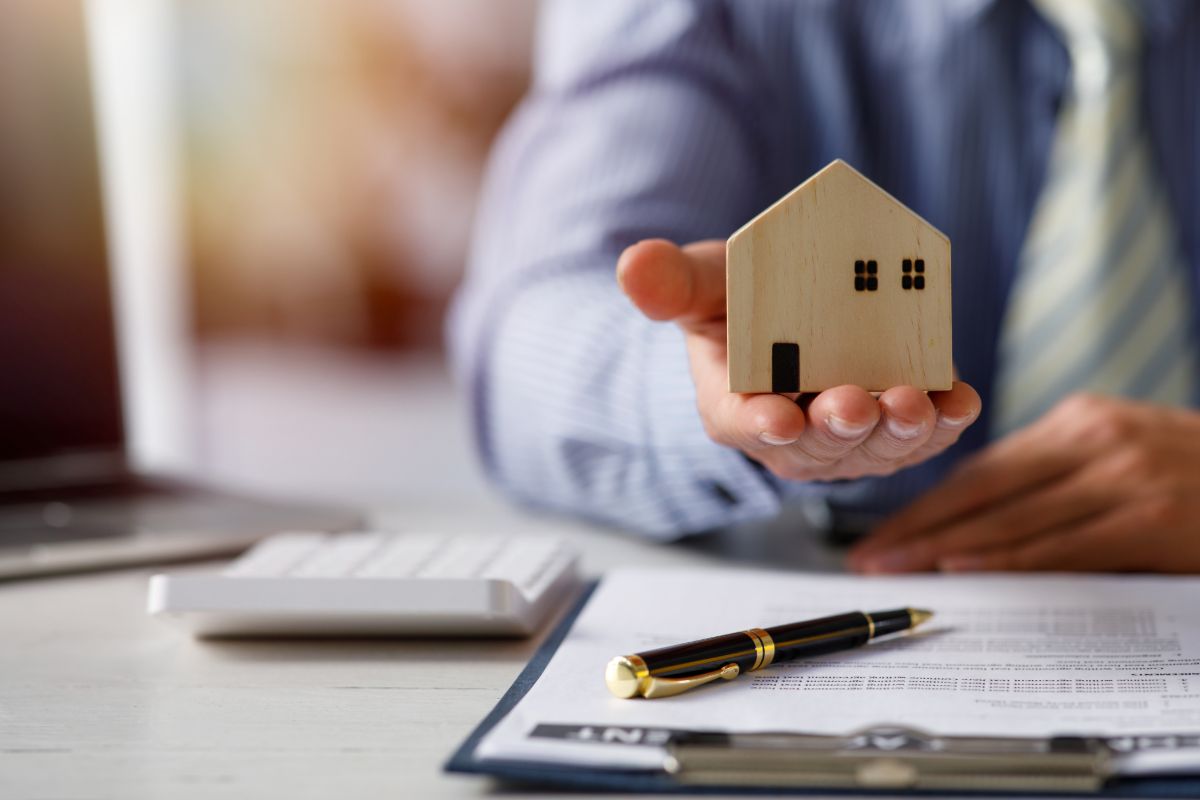 Professional holding a model house during a real estate consultation
